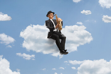 Mature male artist playing a saxophone seated on a cloud