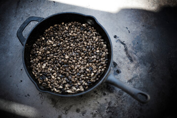 coffee beans being roasted in iron pot.