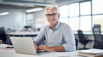 Middle aged man working on a laptop in his modern office