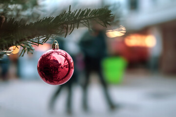 Nahaufnahme einer roten glänzenden Christbaumkugel an einem Zweig einer weihnachtlich...