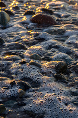 Background: Closeup view of the seawater at sunset. Golden hour. Splashes of water, water bubbles.