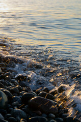 Background: Closeup view of the seawater at sunset. Golden hour. Splashes of water, water bubbles.