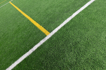 Green artificial grass turf soccer football field background with white and yellow line boundary. Top view © vejaa