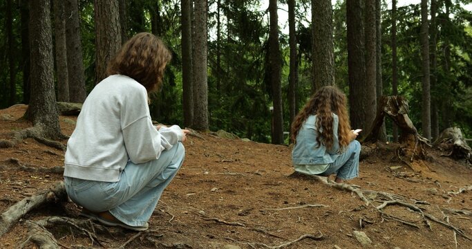 Peer teenage sisters use smartphones for study and classes in forest embrace. A snapshot of homeschooling and nature merger in the digital age. 4k footage. - Powered by Adobe