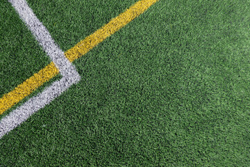 Green artificial grass turf soccer football field background with white and yellow line boundary....