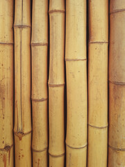 Background of round bamboo trunks. Detail of bamboo reeds. Dry yellow bamboo fence texture horizontal background..
