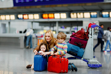 Two tired little kids, boy and girl, siblings and mother at the airport. Children, family...