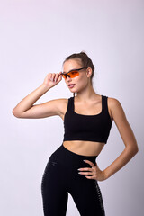Obraz premium Slender young girl with athletic build posing in safety glasses in uniform. Cute cute woman holding glasses with hand on white background, advertising sportswear