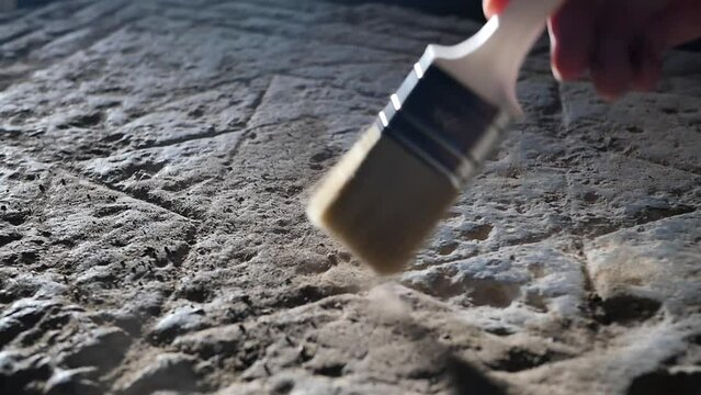 Close-up of an archaeologist's hand using a brush to remove dust from an image of a six-pointed Star of David carved into a stone slab in an ancient temple. Israeli territories. Seal of King Salomon