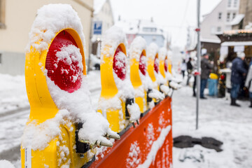 Schneebedeckte Straßenabsperrung mit Warnlampen vor Weihnachtsmarkt
