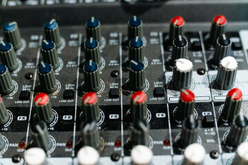 Closeup and detail of audio mixing console with faders and knobs