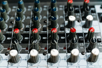 Closeup and detail of audio mixing console with faders and knobs