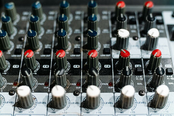 Closeup and detail of audio mixing console with faders and knobs