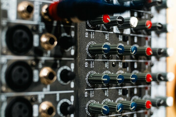 Closeup and detail of audio mixing console with faders and knobs