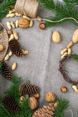 Nuts, cones, pine twigs, a wreath of branches on a linen fabric background