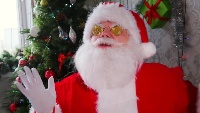 Merry celebration of holiday season with Santa dancing with gold bitcoin cryptocurrency in hands and at eyes. Concept of electronic payments and the potential for wealth creation. Close up.