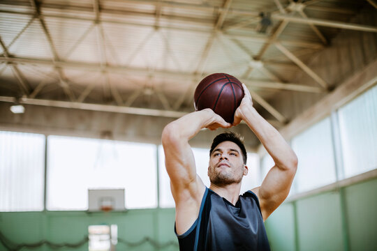 Young man shooting a basketball in an indoor basketball gym