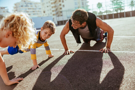 Father and kids doing push-ups together outdoors