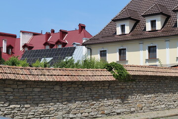 Fototapeta na wymiar Modern private houses with solar panels. Modern houses are surrounded by an old stone wall.