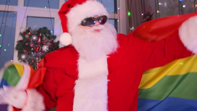 Santa Claus dancing with LGBT flag close up. Liberal values, tolerance, diversity and democracy. Happy New Year holiday.