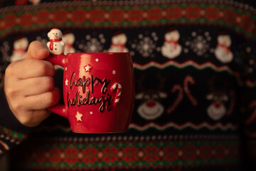Man in Christmas sweater holding a cup of coffee or cacao. Xmas concept.