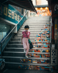 woman walking down seoul south korea stairs in a city market street