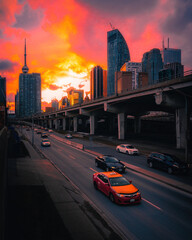 traffic driving through a sunset in Toronto with city skyline skyscrapers