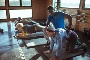 Personal trainer assisting senior woman in gym
