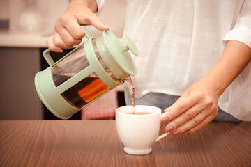 woman pours cup of tea. soothing healthy way to unwind after hard work week