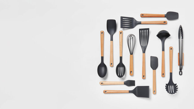Mixed kitchen tools aligned on grey copy-space background.