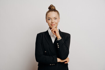 Professional woman in black blazer, thinking pose, white backdrop