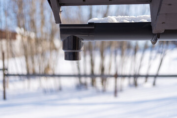 falling drops from melting snow from the roof through the gutters.