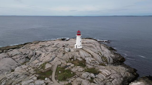 Aerial drone view circling around Peggys Cove lighthouse in Nova Scotia Canada. Beautiful 360 degree view rotating around the famous lighthouse during a calm morning sunrise