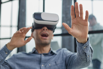 Cool handsome man put on virtual reality goggles for the first time in the office.