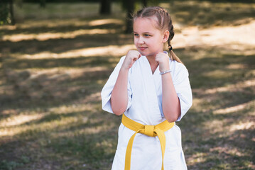 Karateka girl making a hand strike at summer park outdoors. The concept of martial arts - karate, kung fu, taekwondo.