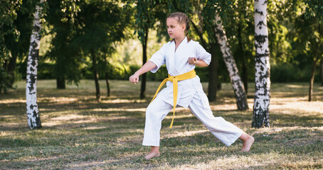 Girl wearing kimono training karate at summer park © VlaDee