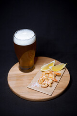 A glass of beer with fired shrimps and lemon
