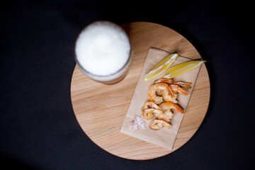 A glass of beer with fired shrimps and lemon