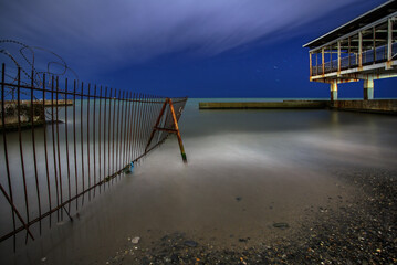 Night on a pebble beach with a pier, long exposure photography - 687261341