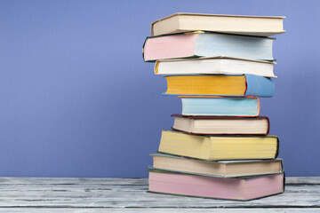 Open stacking book, hardback colorful books on wooden table and blue background. Back to school. Copy space for text. Education business concept.