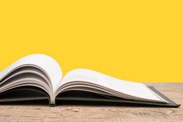 open book. Composition with hardback books, fanned pages on wooden deck table and yellow background. Books stacking. Back to school. Copy Space. Education background.