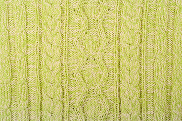 Sweater or scarf fabric texture large knitting. Knitted jersey background with a relief pattern. Braids in knitting . Wool hand- machine, handmade, green.
