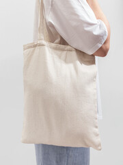 Modern woman carrying textile shopper, eco-friendly linen tote bag on shoulder