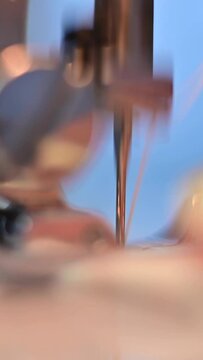 Close-up of a sewing machine needle in the process of sewing. Vertical video. 