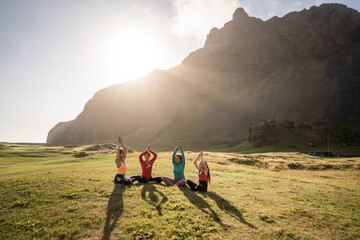 A group of girls meditate at sunset 