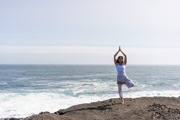 Fototapeta na wymiar A girl does yoga on the ocean