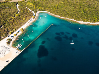 Fototapeta premium A sparkling expanse of turquoise, bordered by a sandy beach and dotted with colorful boats, beckons visitors to explore the untamed beauty of this remote island oasis