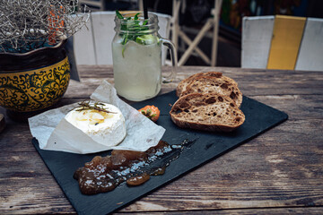 The rustic wooden table was adorned with a tantalizing spread of delectable dishes, including freshly baked bread and a refreshing drink, all surrounded by lush indoor plants, creating a mouth-wateri