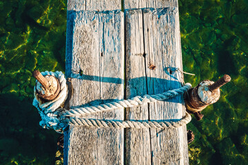 A rustic rope entwined with a sturdy tree, anchoring a wooden dock to the wild outdoors