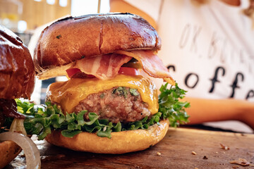 Indulge in a mouth-watering sensation as a person holds an artfully crafted burger with layers of...